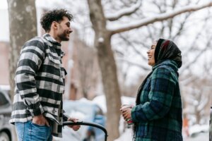 smiling-ethnic-couple-with-stroller-on-sidewalk